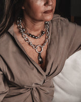 Woman wearing a necklace with a dark pendant in a neutral setting