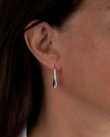 Close-up of a person wearing a silver earring against a neutral background