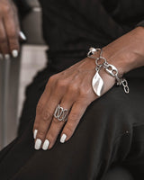 Boho silver spiral statement ring, adjustable design, displayed on a hand with white nails, alongside a silver bracelet.