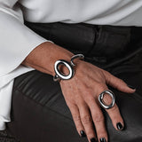 Close-up of a hand wearing a silver ring and bracelet on a dark surface.
