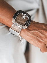 Chunky beige leather cuff bracelet featuring a prominent silver buckle, showcasing a textured finish on the band.
