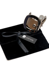 Textured beige leather wide cuff bracelet with a prominent silver buckle, presented in a black velvet pouch.
