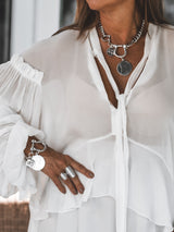 Chunky silver-plated shackle bracelet with large ancient coin pendants worn on a wrist, paired with matching silver rings.