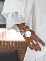 Chunky silver-plated shackle bracelet featuring large vintage coin pendants, showcased on a model’s wrist.
