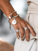 Brown leather wrap cuff bracelet featuring oversized silver-plated horse bit links and coin pendants.