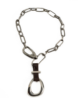 Edgy choker necklace featuring a large silver buckle, hammered iron chain, and a brown leather accent.