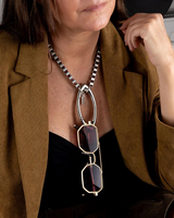 Chunky stainless steel box chain choker featuring a gold carabiner holding stylish sunglasses, worn over a black top.