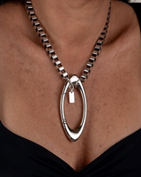 Chunky stainless steel box chain necklace featuring an oversized oval carabiner clasp, worn as a choker.