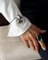 Elegant stainless steel cuff bracelet worn over a white shirt sleeve, featuring two large drops.