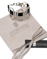 Black leather cuff bracelet featuring shiny oval metal elements, displayed with a suede gift pouch from Otherwise Jewelry.