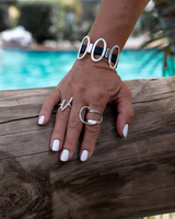 Black leather cuff bracelet featuring shiny oval metal elements worn on a model's wrist, showcasing a chic, casual style.