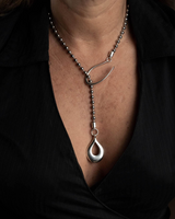 Classy stainless steel chain necklace with a drop pendant, featuring a ball chain and silver hook, worn with a low-cut top.