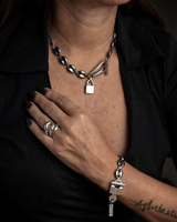 Bold stainless steel choker necklace featuring a padlock pendant and anchor link chain, worn with a black outfit.