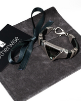 Adjustable black leather bracelet featuring a bold triangular silver-black Austrian crystal centerpiece, resting on a suede pouch.