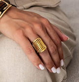Gold plated adjustable statement ring with a bold, chunky design, worn on a hand with neutral nail polish.