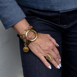 Gold plated adjustable chunky statement ring worn on a woman's hand with a bracelet, showcasing its bold design.