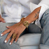 Chunky gold-plated adjustable stainless steel ring worn on a hand, styled with a gold bracelet and casual outfit.
