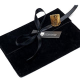 Adjustable golden stainless steel statement ring resting on a black suede pouch with a ribbon, featuring a textured design.