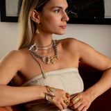 Long, abstract Edgy Chic Earrings in gold and silver, worn by a model with layered necklaces and rings.