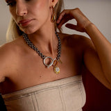 Large, long abstract earrings in silver and gold, worn by a model. Paired with a chunky necklace.