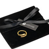 Minimalist unisex ring in gold plating, featuring clean lines, displayed on a black suede pouch with a ribbon.
