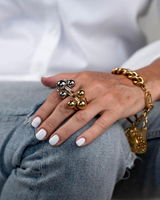 Adjustable stainless steel ring with gold and silver spheres, worn on a hand with white nail polish, paired with a gold chain bracelet.