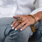 Adjustable stainless steel triple ball ring in gold and silver, worn on a hand with white nails, showcasing chunky spheres.