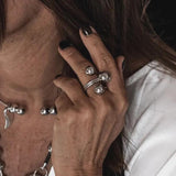 Chunky stainless steel triple ball ring with a modern wrap-around design, worn on fingers with dark nail polish.