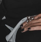 Edgy chic stainless steel ring featuring three large spheres, worn on a manicured hand with black nail polish.