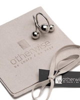 Adjustable stainless steel ring featuring three shiny spheres, presented on a suede pouch with the Otherwise Jewelry logo.