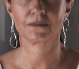 Asymmetric silver dangle earrings with unique hammered lines, showcasing exaggerated design and a bold statement.