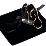Large asymmetric dangle earrings in rose gold with hammered, irregular lines, displayed on a black suede pouch.