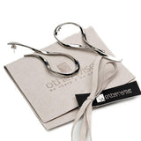 Large asymmetric dangle earrings with hammered metal in silver, featuring exaggerated irregular lines, displayed on a suede pouch.