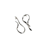 Large asymmetric dangle earrings with irregular hammered lines in silver, showcasing a unique, twisted design.