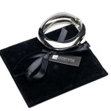 Chunky silver metal cuff bangle resting on a black suede pouch, showcasing a sleek, modern design.