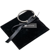 Silver plated open bangle bracelet resting on a black suede pouch, featuring smooth curves and polished ends.