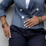 Edgy Chic leather and metal bracelet in brown leather, gold-plated with unique design, worn on wrist with chunky rings.