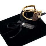 Chunky gold-plated bracelet with a brown textured leather strap, featuring a unique design and adjustable fit.