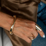 Chunky gold cuff bracelet worn on the wrist, showcasing a smooth, sleek design with a high-polished finish.