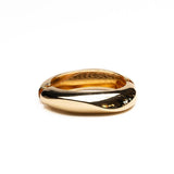 Chunky gold metal cuff bangle with a smooth, twisted design, showcasing a high-polished finish and hollow interior.