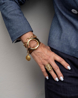 Gold triple wrap bracelet featuring light brown leather and a stainless steel chain, styled on a model’s wrist.