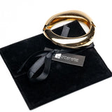Bold chunky gold cuff bangle with a high-polished finish, resting on a black suede pouch.
