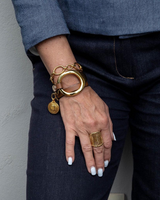 Gold triple wrap bracelet featuring beige leather and a stainless steel chain, worn with a casual denim outfit.