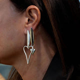 Asymmetric stainless steel heart earrings featuring a long and short design, worn on one ear.