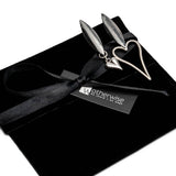 Asymmetric heart earrings featuring a long and a short heart design, presented on a black suede pouch with a ribbon.