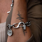 Chunky stainless steel chain bracelet with double lobster clasp and ancient Greek coin pendant, worn on a wrist.