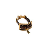 Chunky bracelet featuring a large gold metal plate and soft brown leather strips, adjustable with an extension chain.