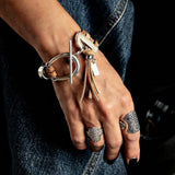 Western style bracelet featuring layered brown suede leather, a silver horsebit buckle, and a tassel.