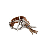 Western style bracelet featuring layered brown suede leather, a silver horsebit buckle, and a tassel detail.
