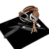 Western style bracelet featuring layered brown suede leather with a horse bit buckle and tassel, presented on a black pouch.